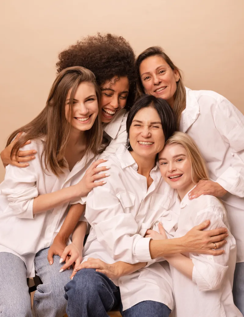 Frauen stehen beieinander umarmen sich und lächeln in die Kamera